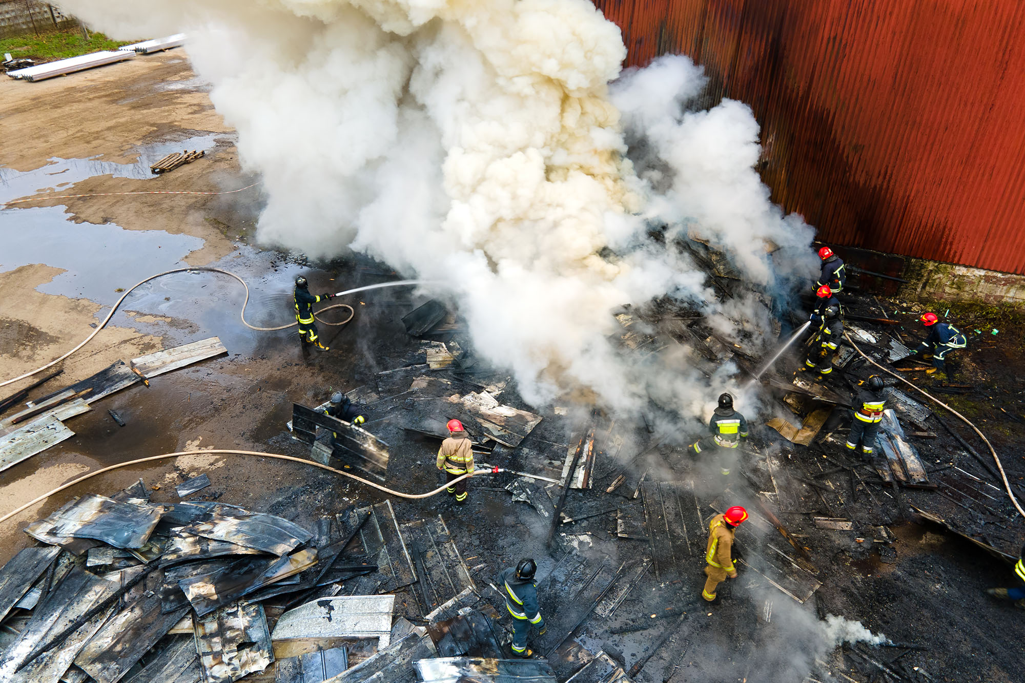 Aerial view of firefighters extinguishing fire in industrial are